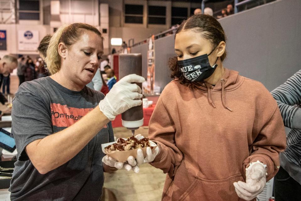 Brenda Baldwin and her daughter Jaylee Baldwin of On the Roll prepare orders during Que the Creek BBQ Festival at Kellogg Arena in Battle Creek on Saturday, Feb. 5, 2022.