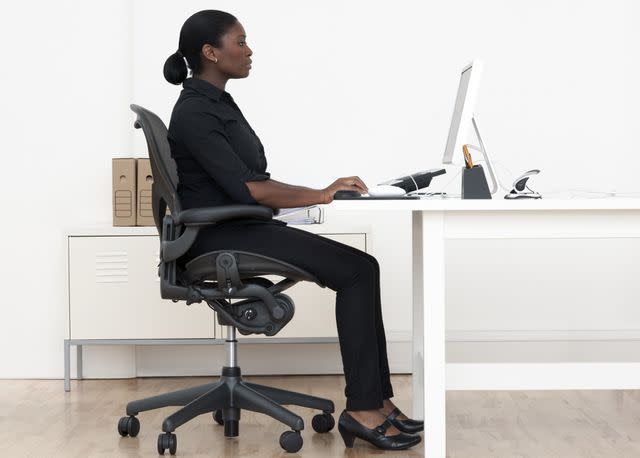 Science Photo Library/Science Photo Library/Getty Images Sitting at a desk can lead to tight quadriceps and low back pain.