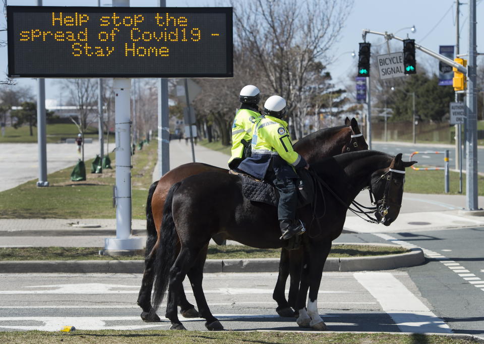 Toronto police officers stop at a red light as they patrol on their service horses in Toronto on Thursday, April 2, 2020. Health officials and the government has asks that people stay inside to help curb the spread of the coronavirus also known as COVID-19. (Nathan Denette/The Canadian Press via AP)