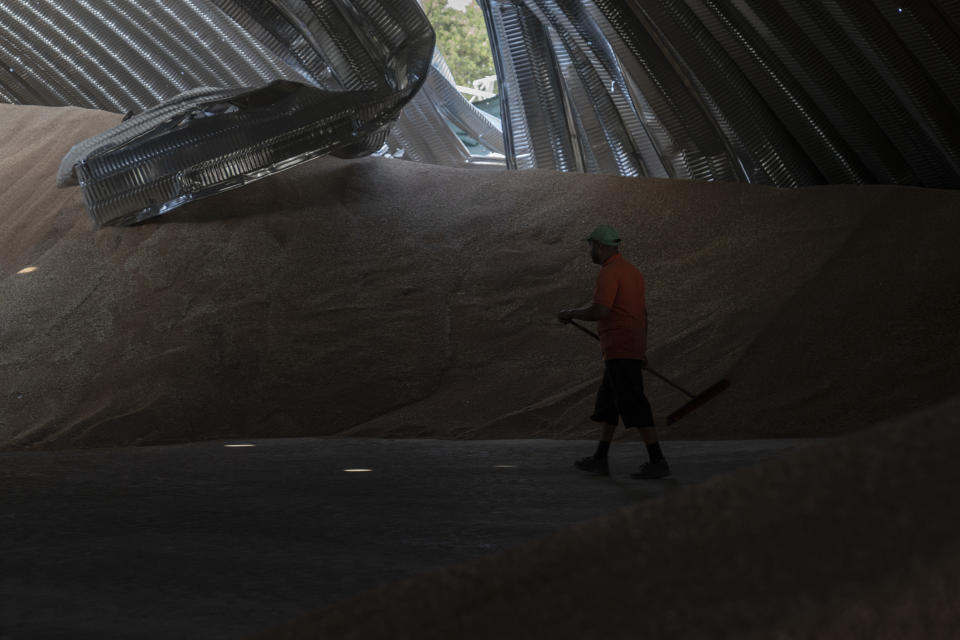 An employee works in a partially damaged warehouse at a grain facility in Pavlivka, Ukraine, Saturday, July 22, 2023, following Russian missile attacks. The collapse of the Black Sea grain deal and a series of missile strikes on Ukrainian grain silos and ports have left farmers with few options to export their grain. (AP Photo/Jae C. Hong)