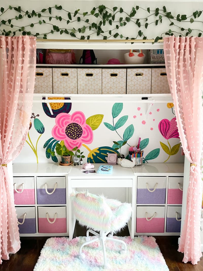 Workspace with colorful painted wall, pink curtains, and lots of colorful storage bins
