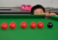 Three-year-old Wang Wuka plays next to a snooker table at home in Xuancheng, Anhui province, September 14, 2013. (REUTERS/Stringer)