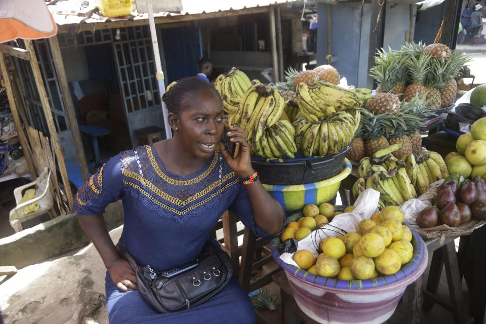 A woman a takes a phone call as she sells fruit on a street in Conakry, Guinea Thursday, Sept. 9, 2021. Guinea's new military leaders sought to tighten their grip on power after overthrowing President Alpha Conde, warning local officials that refusing to appear at a meeting convened Monday would be considered an act of rebellion against the junta. (AP Photo/ Sunday Alamba)