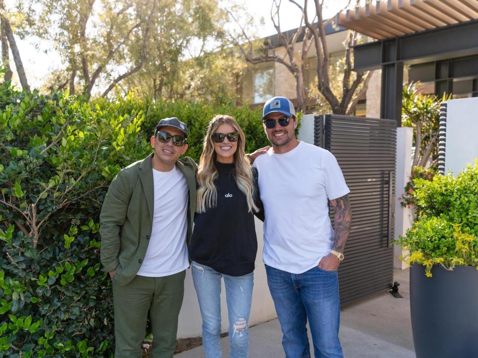 Josh Hall and Christina Hall smile with their realtor outside of their home.