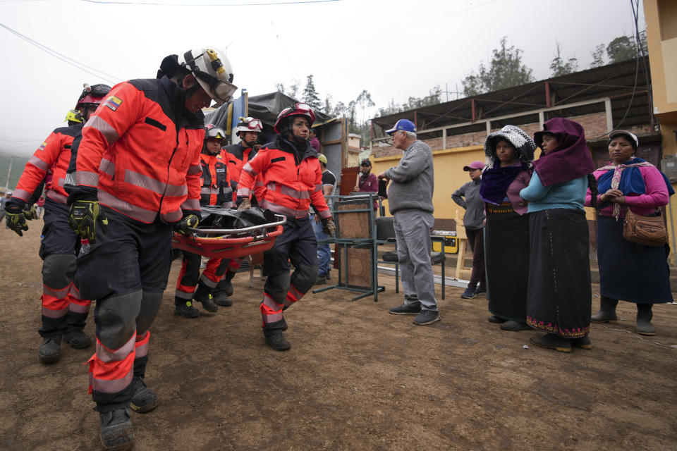 Rescue workers recover the remains of a child in Alausi, Ecuador, Tuesday, March 28, 2023, the day after a landslide swept through the town burying dozens of homes. (AP Photo/Dolores Ochoa)