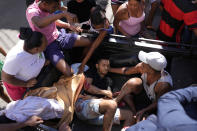 Residents place a wounded man in the back of a truck after a police operation that resulted in multiple deaths, in the Complexo do Alemao favela in Rio de Janeiro, Brazil, Thursday, July 21, 2022. Police said in a statement it was targeting a criminal group in Rio largest complex of favelas, or low-income communities, that stole vehicles, cargo and banks, as well as invaded nearby neighborhoods. (AP Photo/Silvia Izquierdo)