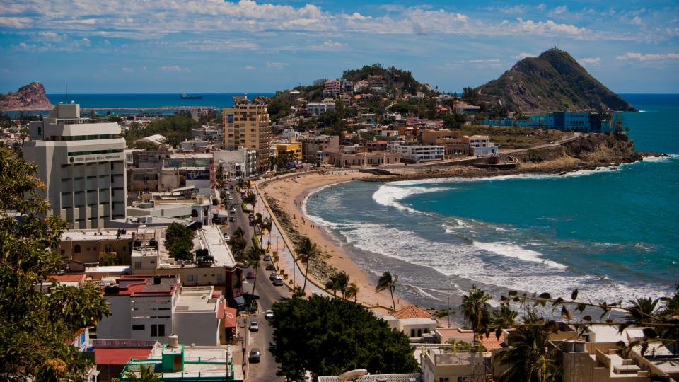 Mazatlán coastline showing palm tree lined roads and a crashing waves.