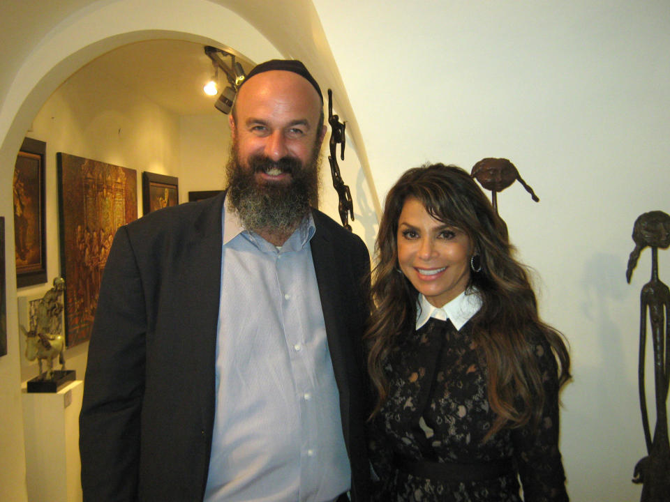 In this Sunday, Nov. 3, 2013 photo released by the Tzfat Kabbalah Center, Rabbi Eyal Riess, left, poses with U.S. singer, dancer, choreographer and TV personality Paula Abdul at the Mikedem Gallery during her Bat Mitzvah in Safed, Israel. Israels Tourism Ministry said Paula Abdul has scaled back a Bat Mitzvah ceremony that shed originally planned to hold at Judaisms holiest site. (AP Photo/Eyal Reiss, Tzfat Kabbalah Center)