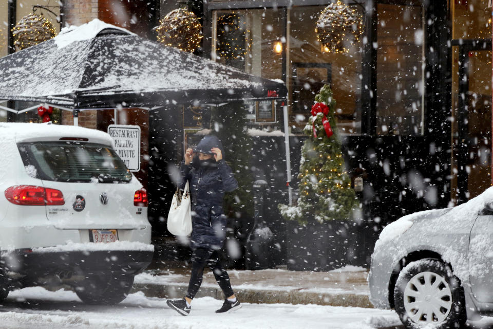 A woman crosses Main Streete during heavy snow, Saturday, Dec. 5, 2020, in downtown Marlborough, Mass. The northeastern United States is seeing the first big snowstorm of the season. (AP Photo/Bill Sikes)