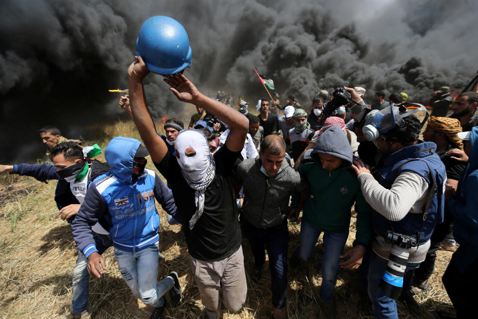 <p>Palestinians evacuate a wounded journalist during clashes with Israeli troops at the Israel-Gaza border at a protest demanding the right to return to their homeland, in the southern Gaza Strip, April 6, 2018. (Photo: Ibraheem Abu Mustafa/Reuters) </p>