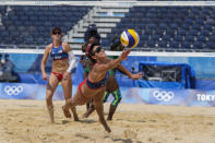 Sarah Sponcil, right, of the United States, dives for the ball as teammate Kelly Claes looks on during a women's beach volleyball match against Kenya at the 2020 Summer Olympics, Thursday, July 29, 2021, in Tokyo, Japan. (AP Photo/Petros Giannakouris)