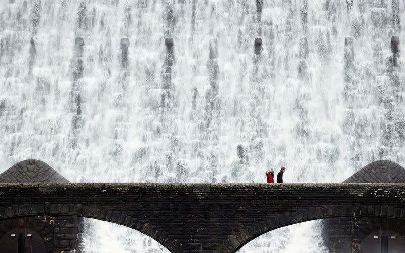 FILE PHOTO: People walk in front of water cascades over the Caban Coch dam in the Elan Valley