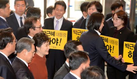 South Korean President Prak Geun-hye (in red) walks past members of the minor opposition Justice Party at the National Assembly in Seoul, South Korea, November 8, 2016. Yonhap/Bae Jae-man/via REUTERS