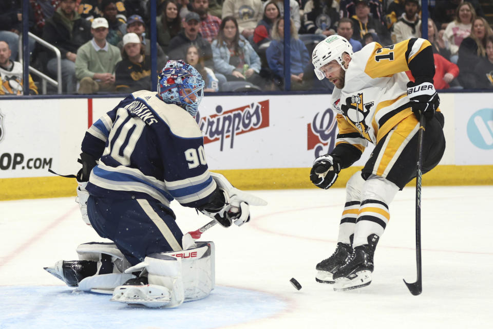 CORRECTS TO BRYAN RUST INSTEAD OF REILLY SMITH Columbus Blue Jackets goalie Elvis Merzlikins, left, makes a stop in front of Pittsburgh Penguins forward Bryan Rust during the first period of an NHL hockey game in Columbus, Ohio, Saturday, March 30, 2024. (AP Photo/Paul Vernon)