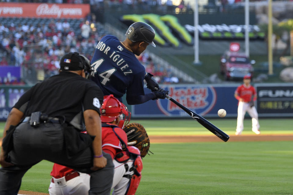 Seattle Mariners' Julio Rodriguez, right, hits a solo home run as Los Angeles Angels catcher Kurt Suzuki, center, watches along with home plate umpire Adrian Johnson during the first inning of a baseball game Saturday, June 25, 2022, in Anaheim, Calif. (AP Photo/Mark J. Terrill)