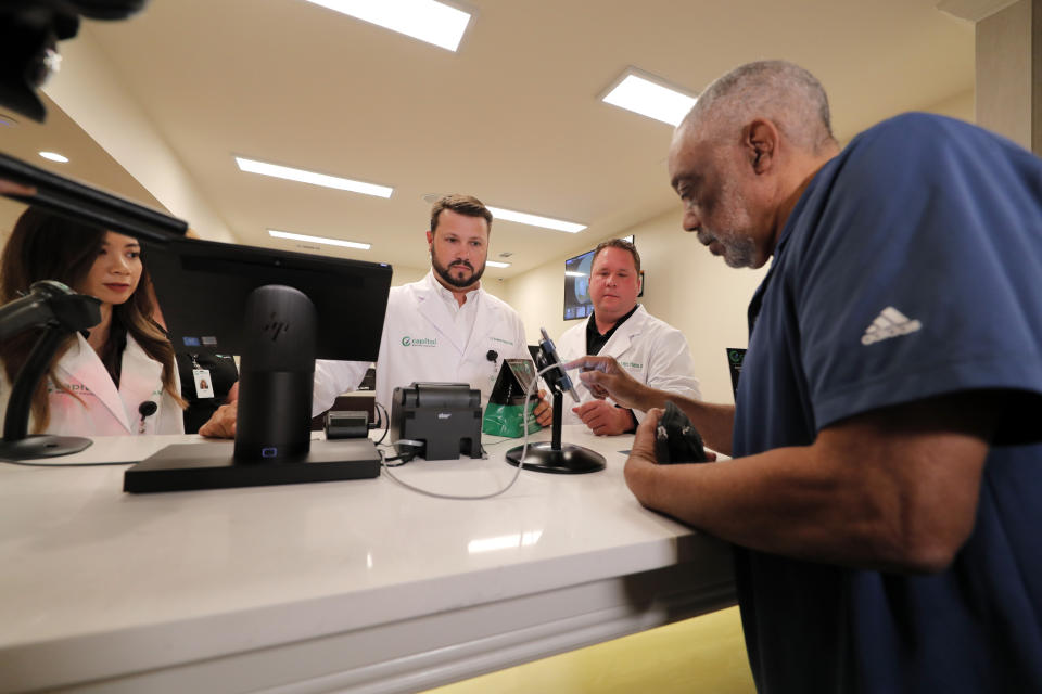 Alex Domino, right, the first ever person to receive medical marijuana in Louisiana, purchases his dose at Capitol Wellness Solutions, in Baton Rouge, La., Tuesday, Aug. 6, 2019. (AP Photo/Gerald Herbert)