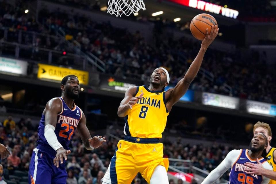The Pacers' Justin Holiday drives to the basket against DeAndre Ayton and the Suns.