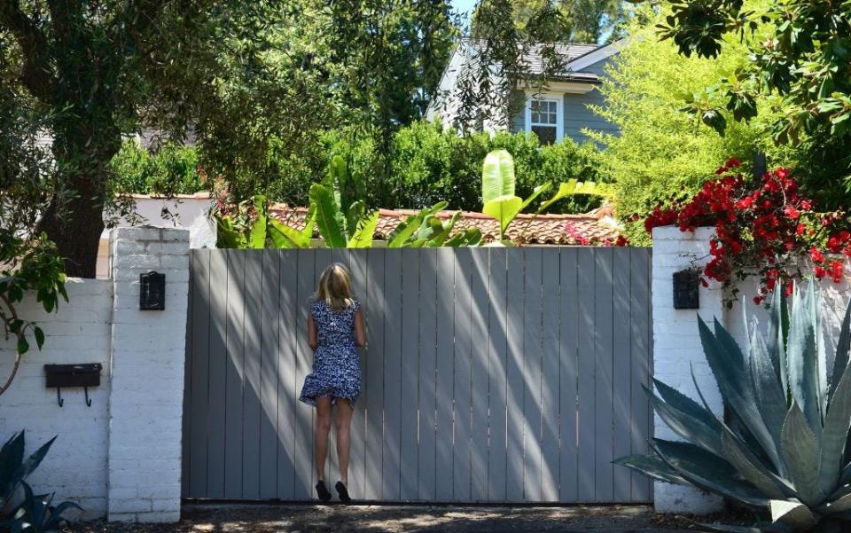 A woman looks for a better view through the gate of the house where Marilyn Monroe died in Brentwood.