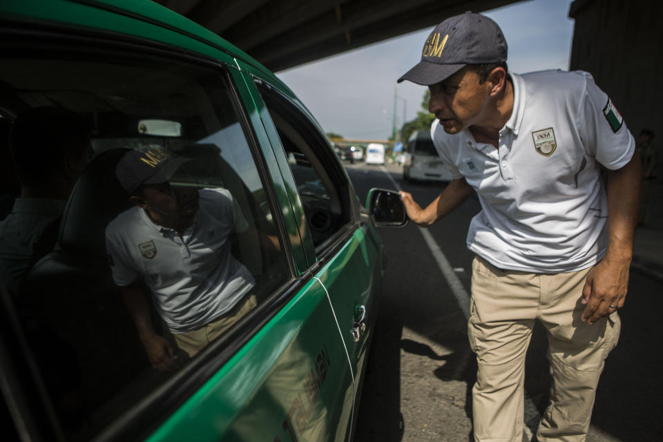 A migration agent checks documents of passengers in passing transport, at an immigration checkpoint in El Manguito, south of Tapachula, Mexico, Friday, June 21, 2019. Mexico's foreign minister says that the country has completed its deployment of some 6,000 National Guard members to help control the flow of Central American migrants headed toward the U.S. (AP Photo/Oliver de Ros)