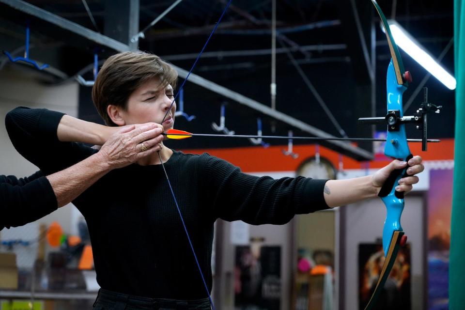 Journal reporter Amy Russo takes aim, under the guiding hand of Heather Dean, during a lesson at Tangy's Archery in Warwick.