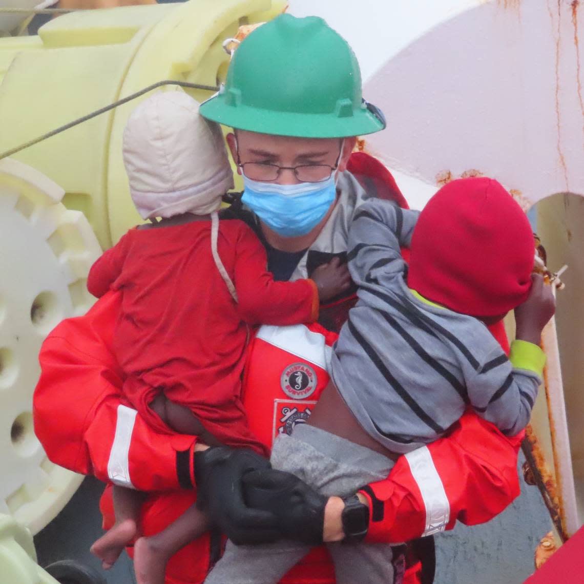 A member of the U.S. Coast Guard holds two babies who were part of a large group of migrants rescued off Key Largo Monday, Nov. 21, 2022.