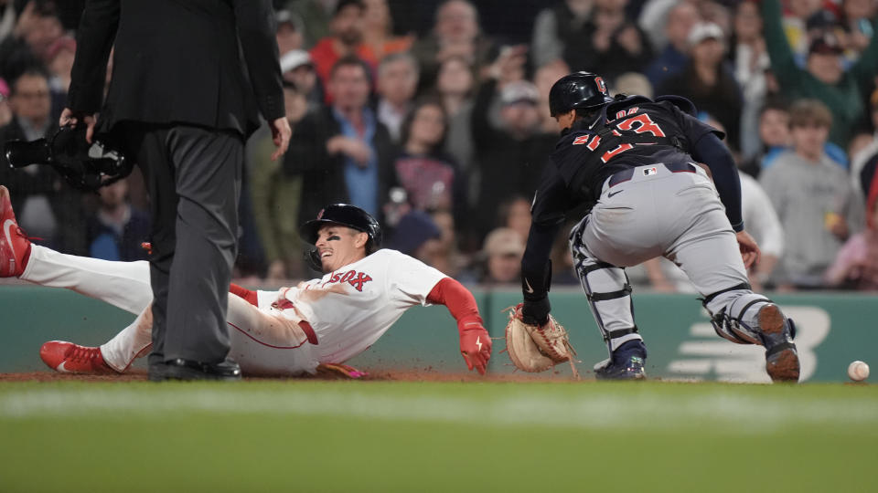 Boston Red Sox's Jarren Duran, left, scores next to Cleveland Guardians' Bo Naylor on a two-run double by Rafael Devers during the sixth inning of a baseball game Tuesday, April 16, 2024, in Boston. (AP Photo/Steven Senne)
