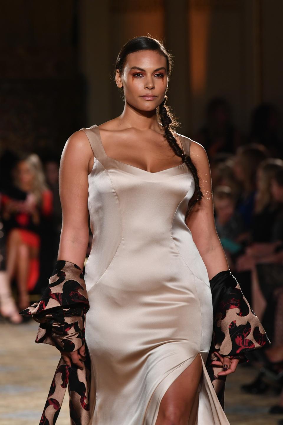 A gorgeous curvy model wears a form-fitting nude satin dress at the Christian Siriano Fall/Winter 2017 Show.