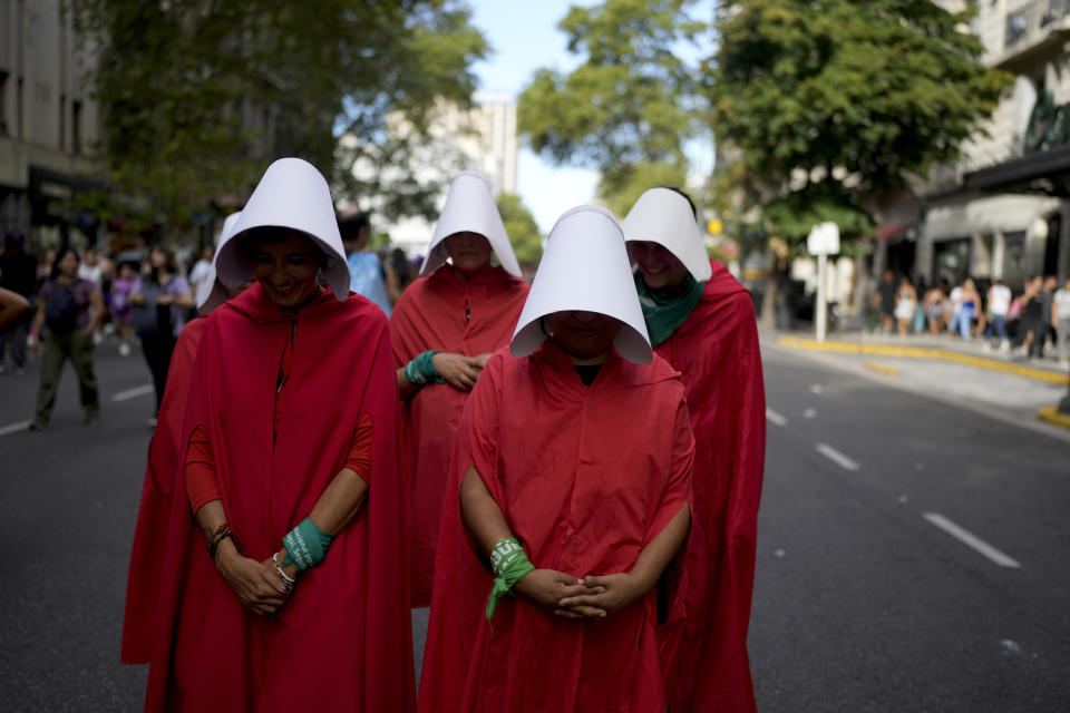 Un grupo de mujeres con capas rojas y sombreros blancos, vestidas como los personales de la novela adaptada a serie televisiva de "El cuento de la criada", marchan en silencio en el Día Internacional de la Mujer en Buenos Aires, Argentina, el viernes 8 de marzo de 2024. (AP Foto/Natacha Pisarenko)