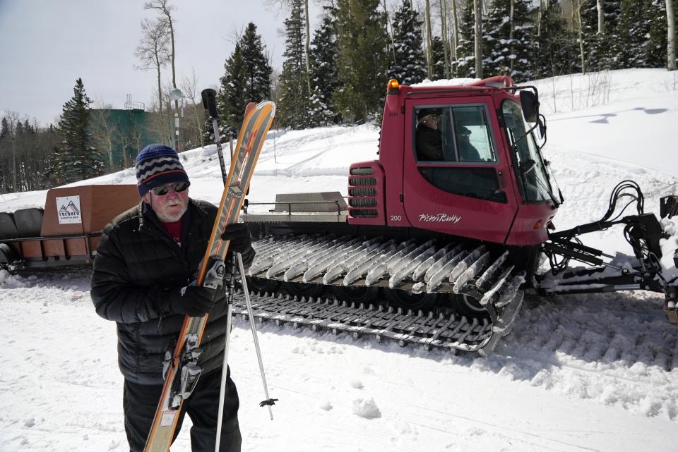 Mike Moore, who worked at Parker-Fitzgerald Cuchara Mountain Park before it closed in 2000, retrieves his skis from the trailer at the top of a hill Sunday, March 19, 2023, near Cuchara, Colo. Some communities including Cuchara are now finding a niche, offering an alternative to endless lift lines and sky-high ticket prices. They're reopening, several as nonprofits, offering a mom-and-pop experience at a far lower cost than mountains run by corporate conglomerates. (AP Photo/Brittany Peterson)