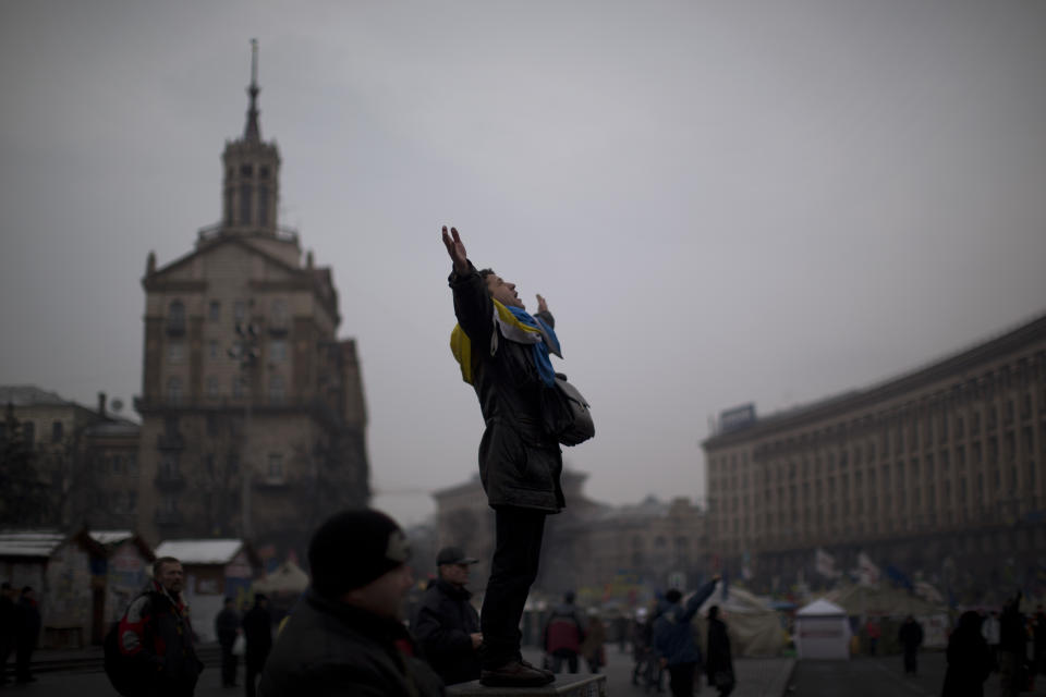 An opposition supporter wearing a Ukrainian flag gestures as he sings the national anthem in the center of Kiev's Independence Square, the epicenter of the country's current unrest, Ukraine, Friday, Feb. 7, 2014. Ukrainian protesters lambasted parliament on Thursday for its lack of action, and a senior U.S. diplomat arrived in Kiev to try to help find a resolution to the country's grinding political crisis. Assistant Secretary of State Victoria Nuland met separately with President Viktor Yanukovych and with opposition leaders during her two-day stay in the Ukrainian capital. (AP Photo/Emilio Morenatti)