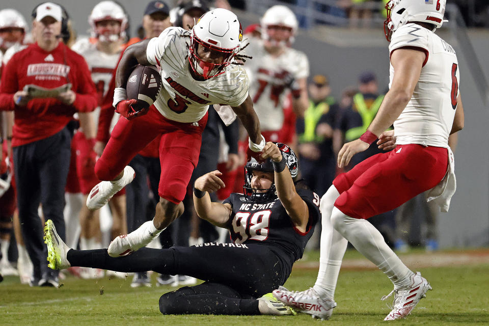 Louisville's Kevin Coleman (3) jumps over the attempted tackle of North Carolina State's Aiden Arias (92) during the second half of an NCAA college football game in Raleigh, N.C., Friday, Sept. 29, 2023. (AP Photo/Karl B DeBlaker)