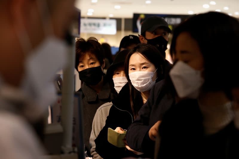 People wearing masks to prevent contracting the coronavirus wait in line to buy masks at a department store in Seoul