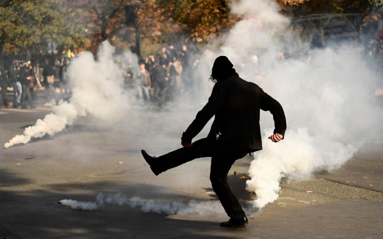 Demonstrator kicks a tear gas canister during a rally to protest the French government's proposed reforms in labour laws on September 21, 2017, in Paris - AFP