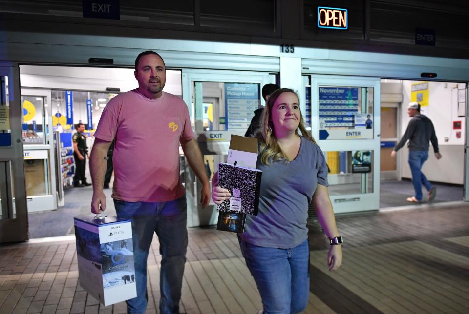 Black Friday shoppers Zach and Cyndi Spellman of Parrish, emerge from Best Buy with their early morning purchases in hand. The Spellmans were first in line at the electronics store which opened at 5 a.m. at University Town Center, and were headed to Walmart next to get in line before that store opens at 6 a.m. on Friday morning, Nov. 25, 2022 in Sarasota.