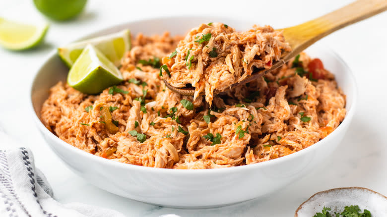 Shredded salsa chicken being spooned out of bowl
