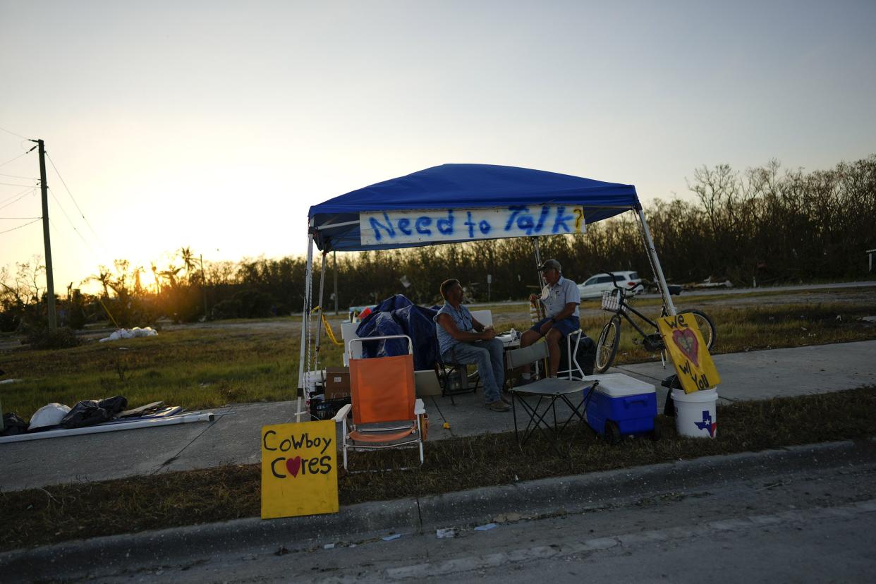 "Cowboy" Dave Graham of Ohio, left, who travels to communities that have suffered traumatic events to offer support by listening to survivors, speaks with John, a resident of San Carlos Island whose mobile home was destroyed in Hurricane Ian, in Fort Myers Beach, Fla., Saturday, Oct. 1, 2022.