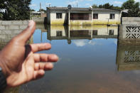 A man points to a house submerged in water caused by Cyclone Idai in Inchope, Mozambique, Monday March 25, 2019. Cyclone Idai's death toll has risen above 750 in the three southern African countries hit 10 days ago by the storm, as workers rush to restore electricity, water and try to prevent outbreak of cholera. (AP Photo/Tsvangirayi Mukwazhi)