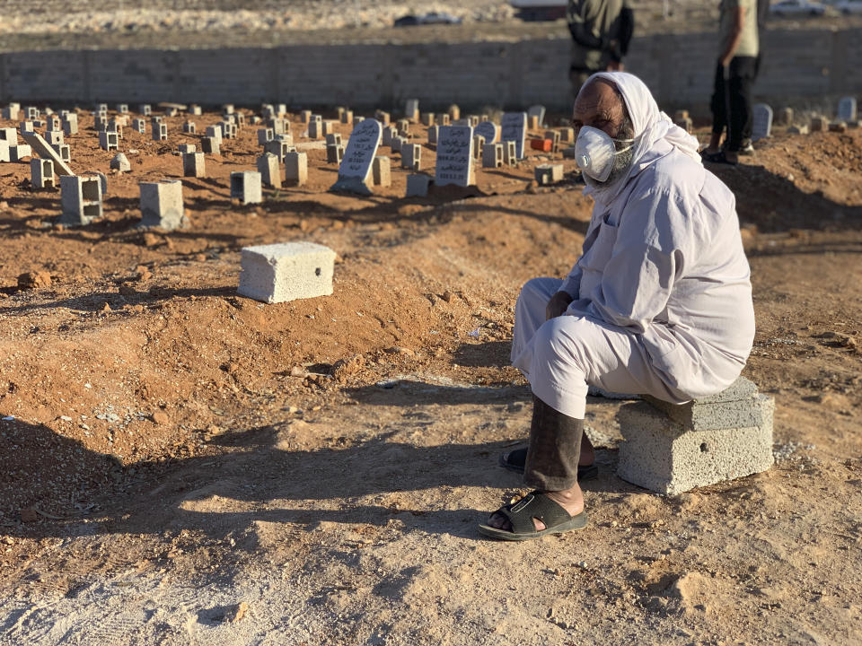 A man sits by the graves of the flash flood victims in Derna, Libya, Friday, Sept. 15, 2023. The death toll in Libya's coastal city of Derna has soared to over ten thousand as search efforts continue following a massive flood fed by the breaching of two dams in heavy rains, the Libyan Red Crescent said Thursday. (AP Photo/Yousef Murad)
