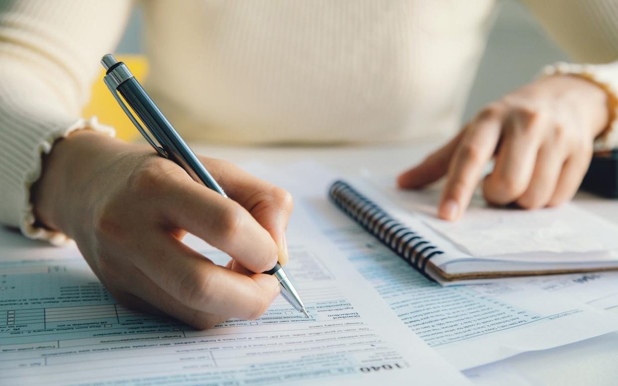 Closeup woman filling form of Individual Income Tax Return, - Getty Images/iStockphoto