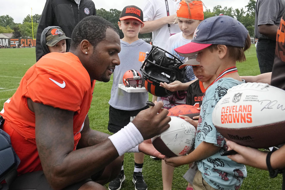 Cleveland Browns quarterback Deshaun Watson, left, gives autographs to young fans after an NFL football camp, Monday, Aug. 7, 2023, in Berea, Ohio. (AP Photo/Sue Ogrocki)