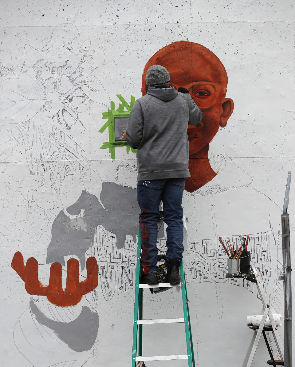 In this Dec. 13, 2018, photo, Muhammad Yungai paints mural on a building near the Mercedes Benz Stadium in Atlanta. A series of about 30 murals on walls around the downtown Atlanta stadium that will host the Super Bowl aims to highlight Atlanta's civil rights legacy. The murals are part of an initiative called "Off The Wall: Atlanta's Civil Rights and Social Justice Journey." (AP Photo/John Bazemore)