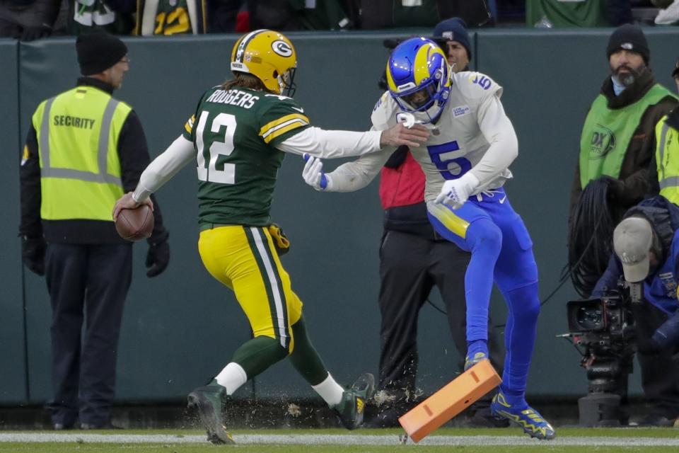 Green Bay Packers' Aaron Rodgers runs past Los Angeles Rams' Jalen Ramsey for a touchdown during the first half of an NFL football game Sunday, Nov. 28, 2021, in Green Bay, Wis. (AP Photo/Aaron Gash)