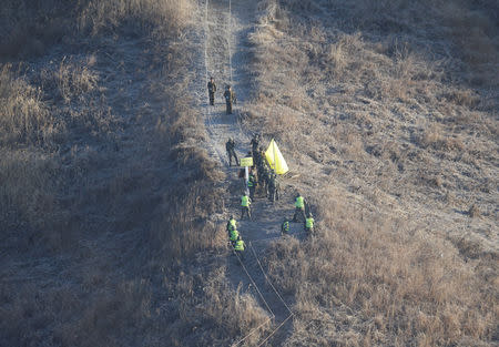 South Korean army soldiers, wearing yellow head bands, cross the Military Demarcation Line inside the Demilitarized Zone (DMZ) to inspect the dismantled North Korean guard post in the central section of the inter-Korean border in Cheorwon, Korea, Wednesday, Dec. 12, 2018. Ahn Young-joon/Pool via REUTERS