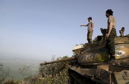 Rebel fighters stand on a tank overlooking al-Ghab plain, in the Jabal al-Akrad area in Syria's northwestern Latakia province, April 29, 2015. REUTERS/Khalil Ashawi