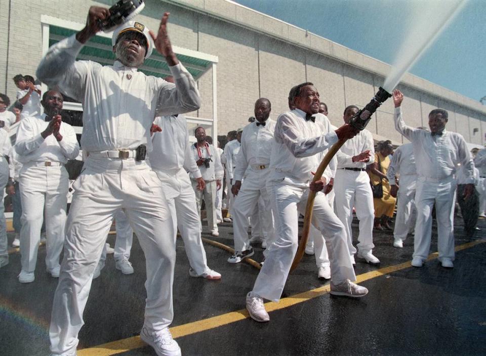 10/11/98 (L-R) Billy Hoover plays the tambourine Sunday morning as a church leader sprays water onto a crowd of thousands during a baptismal service at the the United House of Prayer for All People on Freedom Drive.