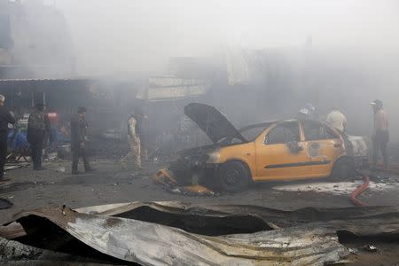 Iraqi security forces and civilians gather at the site of a car bomb attack in Baghdad al-Jadida, Iraq April 25, 2016. REUTERS/Ahmed Saad