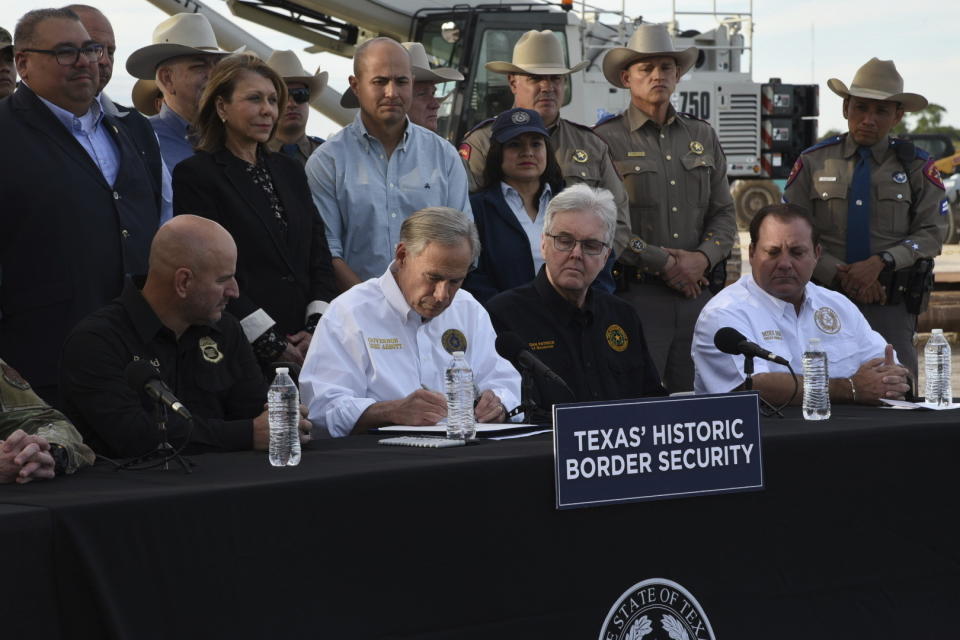 El gobernador de Texas, Greg Abbott, promulga tres iniciativas de ley el lunes 18 de diciembre de 2023, en un sitio ubicado frente al muro fronterizo, en Brownsville, Texas. (AP Foto/Valerie Gonzalez)