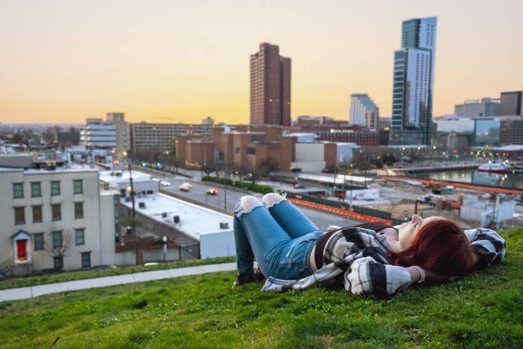 A woman lays on a hill overlooking Baltimore. 