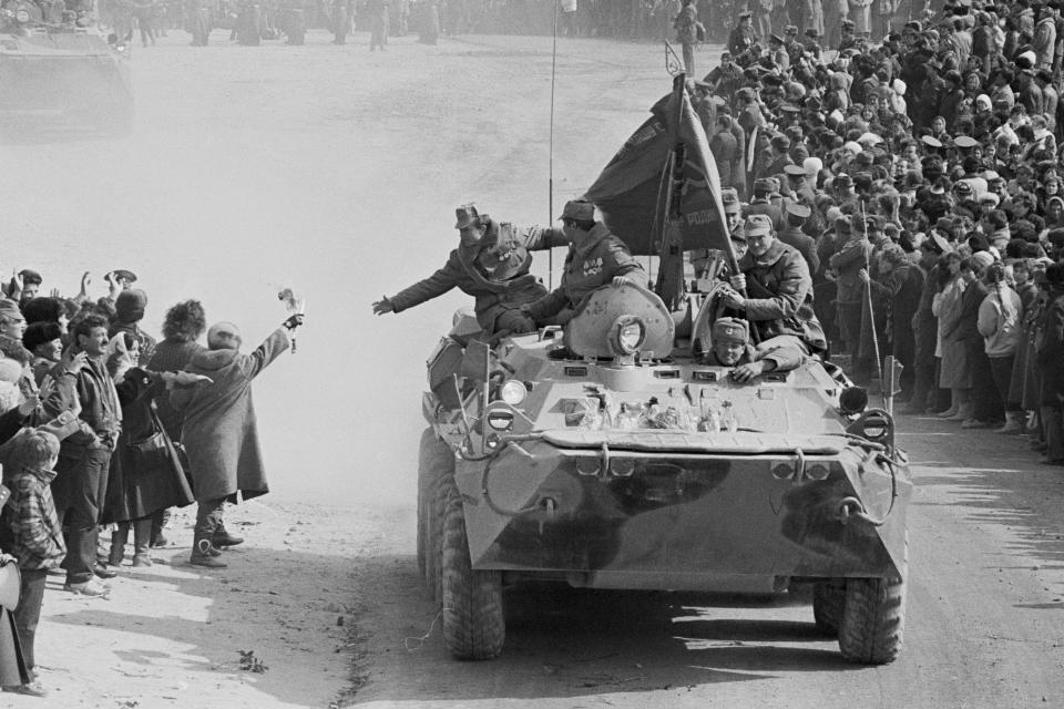 FILE - People and relatives greet Soviet Army soldiers driving on their armored personnel carriers after crossing a bridge on the border between Afghanistan and then Soviet Uzbekistan near the Uzbek town of Termez, Uzbekistan in Feb. 15, 1989. After nearly a decade of fighting in Afghanistan, he ordered the withdrawal of Soviet troops in 1989, entered into multiple arms control and disarmament agreements with the United States and other countries, and helped end the Cold War. (AP Photo/Alexander Zemlianichenko, File)