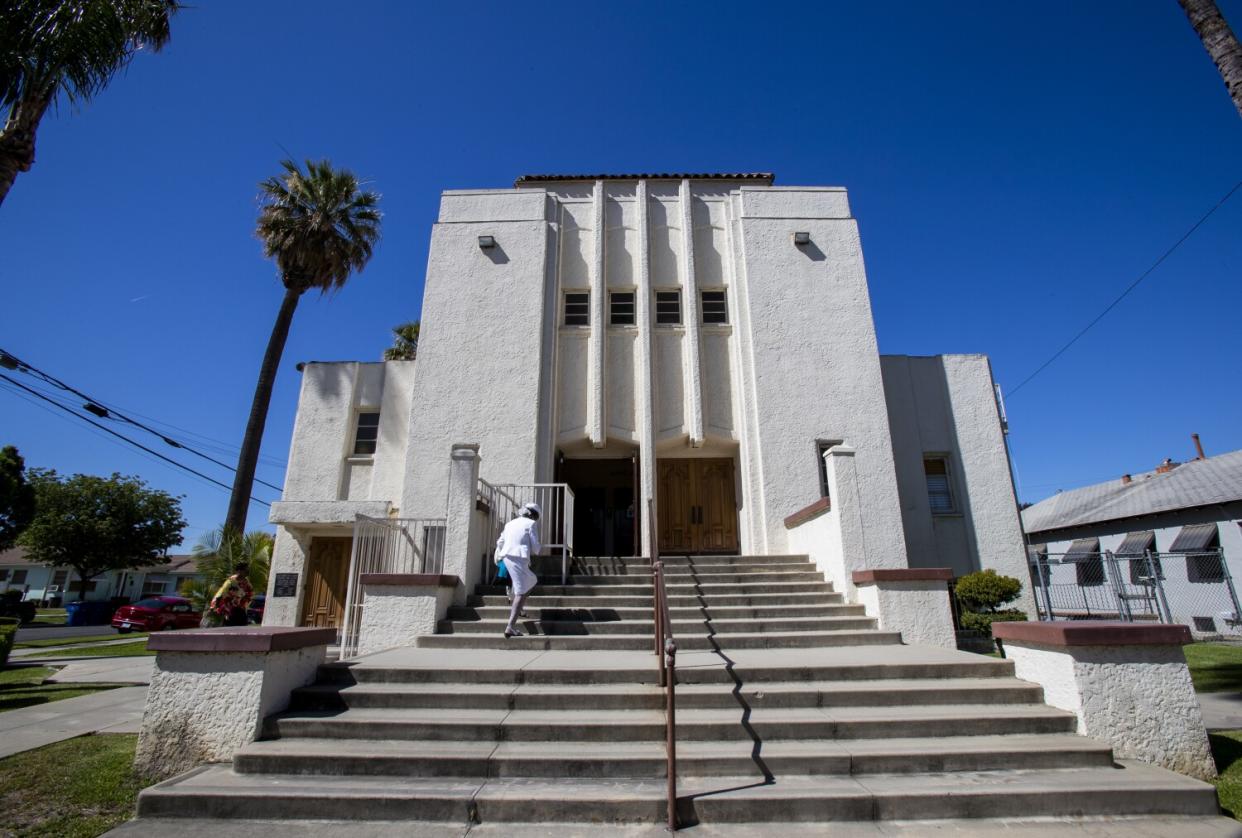 A person walking up a wide stairway to a stucco building